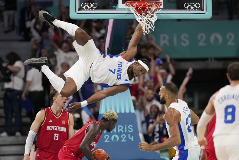El francés Guerschon Yabusele cuelga del aro tras realizar una clavada ante Alemania, el viernes 2 de agosto de 2024, en los Juegos Olímpicos. El encuentro se disputó en Villeneuve-dAscq, Francia. (AP Foto/Mark J. Terrill)