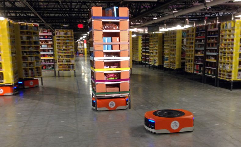 Imagen de un robot Kiva, al frente, antes de transitar entre estanter&iacute;as de mercanc&iacute;a en el nuevo centro de distribuci&oacute;n de Amazon en Tracy, California, el domingo 30 de noviembre de 2014. (Foto AP/Brandon Bailey)