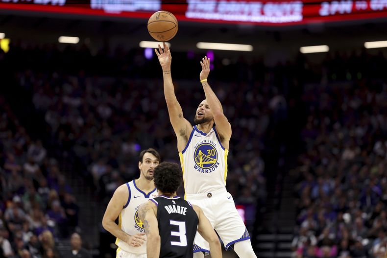 Stephen Curry, base de los Warriors de Golden State, dispara frente a Chris Duarte, de los Kings de Sacramento, en el duelo del viernes 27 de octubre de 2023 (AP Foto/Jed Jacobsohn)