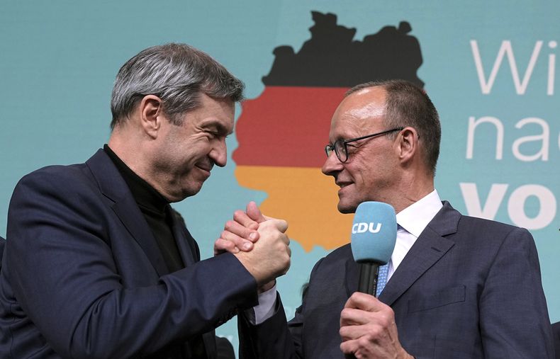 Friedrich Merz, a la derecha, líder de la Unión Democristiana (CDU), y Markus Soeder, líder de la Unión Social Cristiana (CSU), se estrechan la mano en la sede de la CDU en Berlín, Alemania. el domingo 23 de febrero de 2025. (Michael Kappeler/dpa via AP)