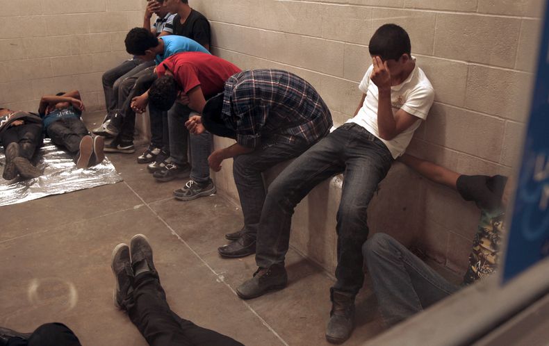 Inmigrantes que han sido detenidos al cruzar la frontera se ocultan el rostro dentro de la estación de la Patrulla Fronteriza en McAllen, Texas, el martes 15 de julio de 2014. El Salvador, Guatemala y Honduras pedirán al presidente estadouni