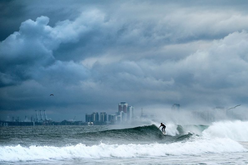 Un surfista monta una ola mientras se forman nubes en la playa estatal de Bolsa Chica, en el condado de Orange, California, el sábado 15 de noviembre de 2025. (AP Foto/Noah Berger)