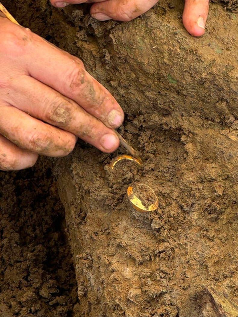 En esta foto difundida por el Departamento de Bellas Artes, un arqueólogo muestra dos anillos con huesos humanos durante una excavación en el sitio arqueológico de Don Yai Thong, en la provincia de Phetchaburi, Tailandia, el jueves 2 de julio de 2026. (Departamento de Bellas Artes vía AP)