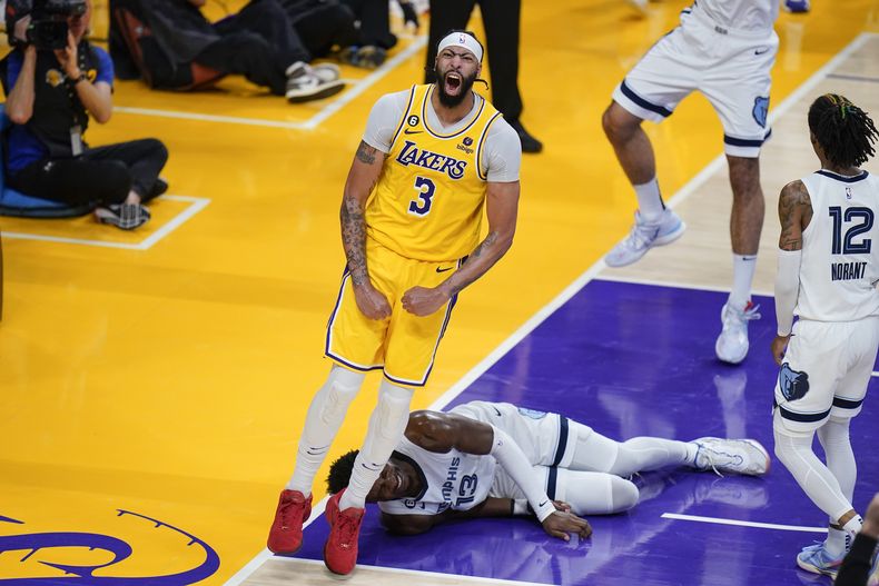 Anthony Davis, de los Lakers de Los Ángeles, festeja su volcada frente a Jaren Jackson, de los Grizzlies de Memphis, quien yace en el suelo en el encuentro de playoffs disputado el viernes 28 de abril de 2023 (AP Foto/Jae C. Hong)