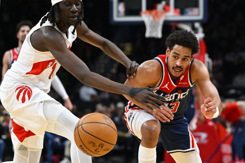 El escolta de los Wizards de Washington, Jordan Poole, a la derecha, pierde el control del balón contra el alero de los Raptors de Toronto, Mouhmamdou Gueye, a la izquierda, durante la segunda mitad de un partido de baloncesto de la NBA, el sábado 23 de marzo de 2024, en Washington. (AP Foto/John McDonnell)