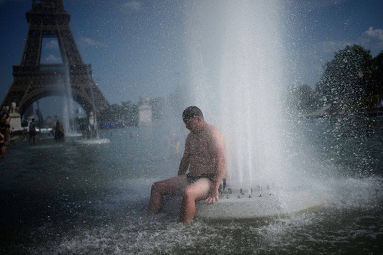 Una persona se refresca en una fuente en el Trocadero, cerca de la Torre Eiffel, durante una ola de calor, en París, el 24 de junio de 2026. (AP Foto/Christophe Ena)