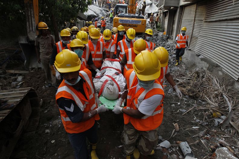 Rescatistas llevan el cuerpo de un trabajador extra&iacute;do entre los escombros de un edificio que se derrumb&oacute; el s&aacute;bado pasado durante lluvias intensas en Chennai, India, 30 de junio de 2014. (AP Foto/Arun Sankar K)