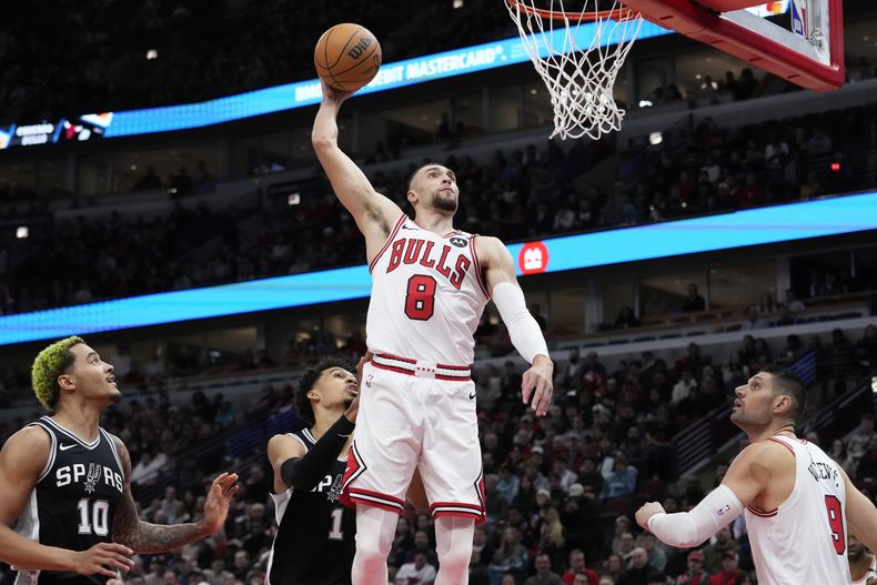 El base de los Bulls de Chicago Zach LaVine salta para clavar el balón frente al pívot de los Spurs de San Antonio Victor Wembanyama en el encuentro de la NBA del lunes 6 de enero del 2025. (AP Foto/Nam Y. Huh)