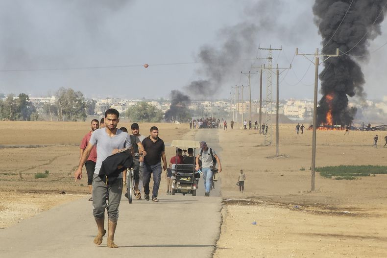 Palestinos se alejan del kibbutz de Kfar Azza, Israel, cerca de la valla fronteriza de la Franja de Gaza, el 7 de octubre de 2023. (AP Foto)