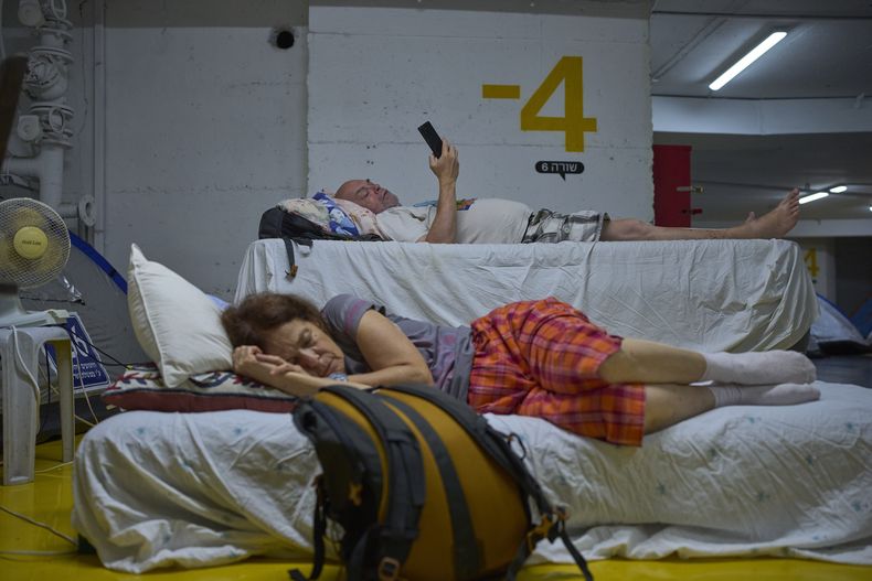 Gente pasa la noche en un estacionamiento como precaución contra posibles ataques de misiles iraníes en Tel Aviv, Israel, el lunes 23 de junio de 2025. (AP Foto/Ohad Zwigenberg)