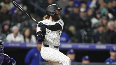 Charlie Blackmon, de los Rockies de Colorado, sigue el vuelo de la pelota de un doble que imphlsó dos carreras ante el relevista de los Rangers de Texas, Yerry Rodríguez, en la octava entrada del juego de béisbol el viernes 10 de mayo de 2024, en Denver. (AP Foto/David Zalubowski)