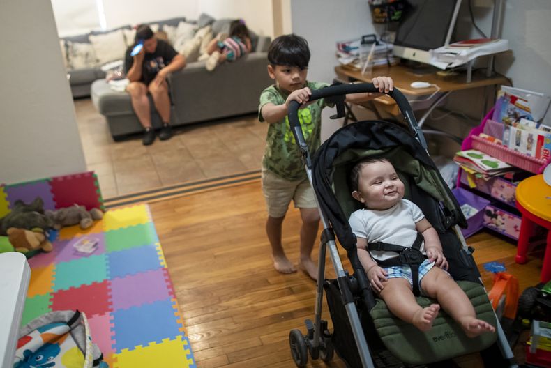 Stefano López, de 5 años, empuja el carro de su hermano Adonai, de 8 meses, mientras su madre, la solicitante de asilo venezolana Oriana Marcano, escucha su celular el viernes 12 de mayo de 2023, en El Paso, Texas. Cuando la familia se perdió el año pasado en la selva del Darién, su esposo, Luis López, se arrodilló en el lodo para suplicar a Dios que no les abandonara. (AP Foto/Andrés Leighton)