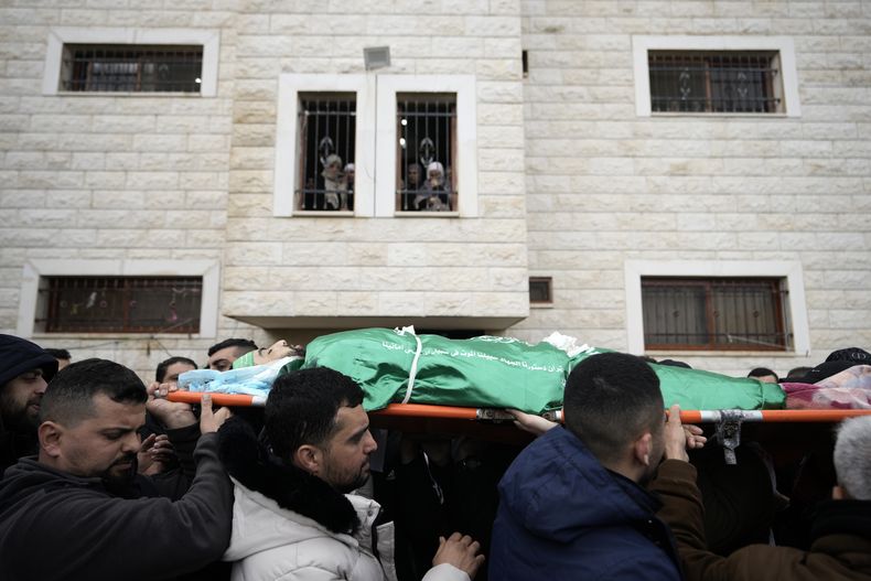 Dolientes palestinos cargan el cuerpo de Muhammad Jalamneh, envuelto en la bandera del grupo armado Hamás, durante su funeral tras ser asesinado en un asalto a hospital Ibn Sina en la localidad cisjordana de Yenín, el martes 30 de enero de 2024. (AP Foto/Majdi Mohammed)