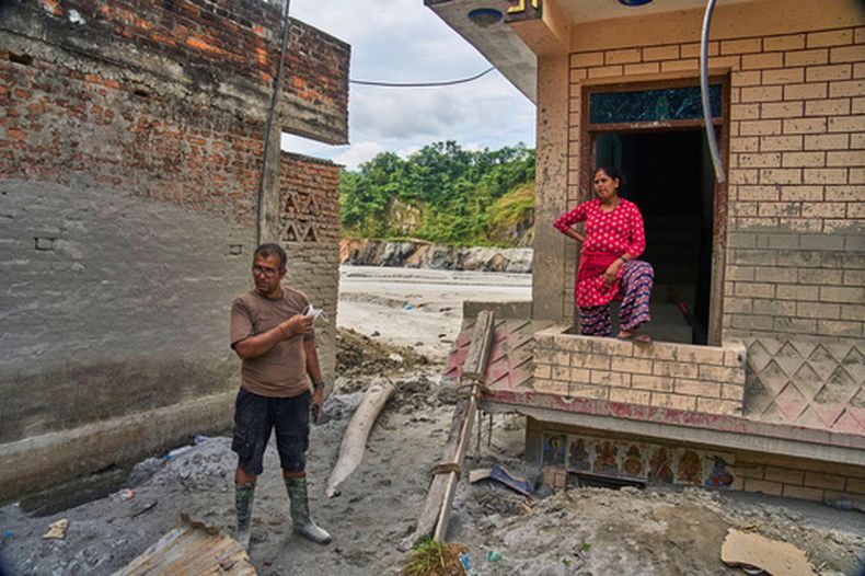Narayan Prasad Nepal (izquierda), en el exterior de su casa, dañada por una inundación repentina, en Galchi, Nuwakot, Nepal, el 23 de septiembre de 2026. (AP Foto/Niranjan Shrestha)