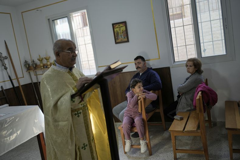 El sacerdote Maurice El Khoury, a la izquierda, dirige una misa en una sala utilizada normalmente como residencia para obispos visitantes cerca de la iglesia católica melquita de San Jorge, que fue destruida en un ataque aéreo israelí, en la localidad de Dardghaya, en el sur de Líbano, el domingo 16 de noviembre de 2025. (AP Foto/Hassan Ammar)