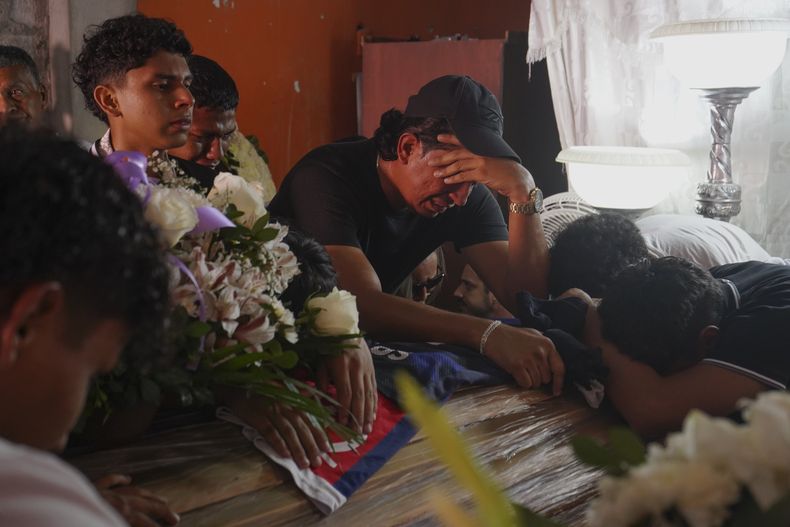 Familiares y amigos lloran sobre los féretros de los hermanos Ismael y Josué Arroyo, dos de cuatro niños que desaparecieron tras jugar al fútbol en diciembre, durante el velorio el 1 de enero de 2025 en la casa de la famlia en Guayaquil, Ecuador. (AP Foto/César Muñoz)