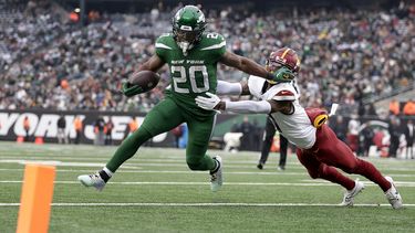 Breece Hall (20), running back de los Jets de Nueva York, se quita con el brazo al safety de los Commanders de Washington Kamren Curl (31) en su camino a la zona de anotación para un touchdown durante el segundo cuarto del partido de la NFL, el domingo 24 de diciembre de 2023, en East Rutherford, Nueva Jersey. (AP Foto/Adam Hunger)