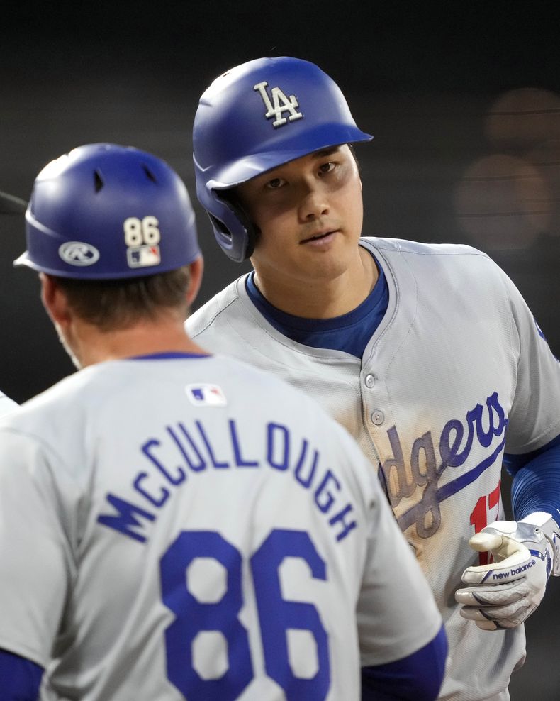 El japonés Shohei Ohtani, de los Dodgers de Los Ángeles, es felicitado por el coach de la inicial Clayton McCullough luego de pegar un sencillo productor en el juego del martes 25 de junio de 2024, ante los Medias Blancas de Chicago (AP Foto/Charles Rex Arbogast)