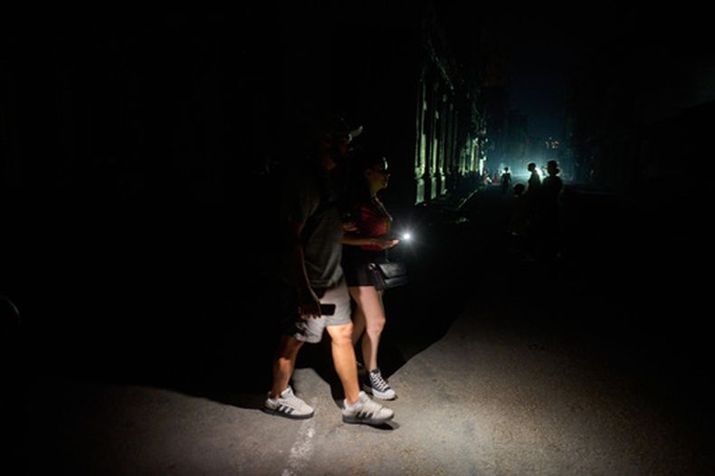 Varias personas caminan por una calle iluminadas con linternas durante un apagón en La Habana, Cuba, el lunes 6 de julio de 2026. (AP Foto/Ramón Espinosa)