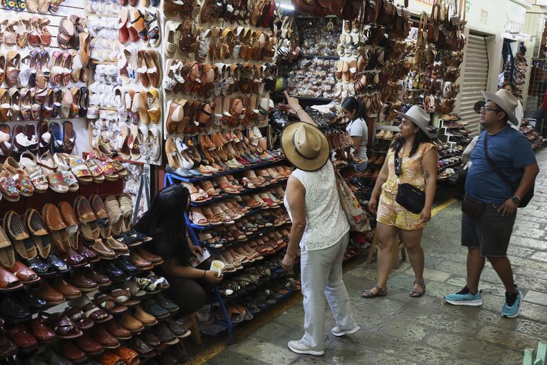 La gente mira una tienda que vende sandalias conocidas como huaraches en un mercado de Oaxaca, México, el viernes 8 de agosto de 2025. (AP Foto/Luis Alberto Cruz)