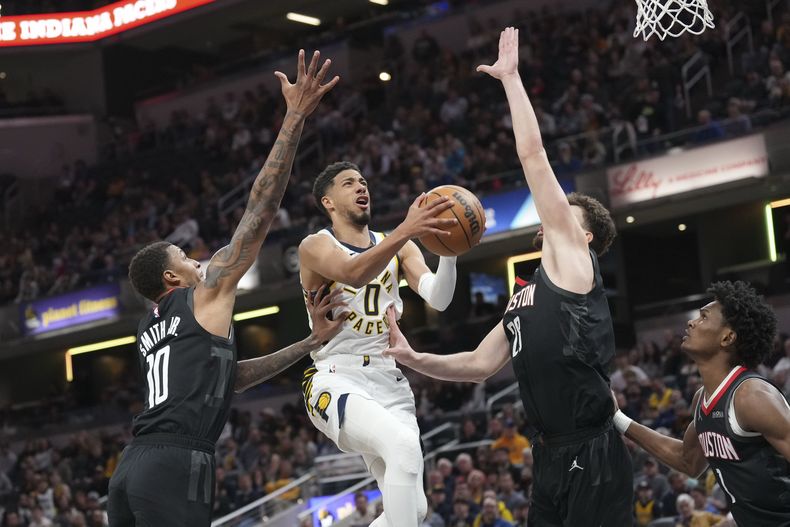 El escolta de los Pacers de Indiana, Tyrese Haliburton, en el centro, dispara entre los defensas de los Rockets de Houston, Jabari Smith Jr., y Alperen Sengun, durante la primera mitad de un partido de baloncesto de la NBA en Indianápolis, el martes 4 de marzo de 2025. (AP Foto/AJ Mast)