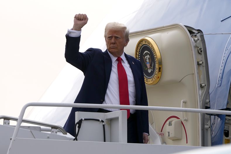 El presidente Donald Trump alza un puño al abordar el Air Force One en dirección a Florida, el sábado 25 de enero de 2025, en el Aeropuerto Internacional Harry Reid en Las Vegas. (AP Foto/Mark Schiefelbein)