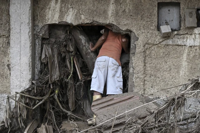 Un residente busca a sus familiares desaparecidos entre los escombros de una casa destruida por un deslizamiento de tierra durante fuertes lluvias en Las Tejerias, estado Aragua, Venezuela, el 9 de octubre de 2022. – Un deslizamiento de tierra en el ce