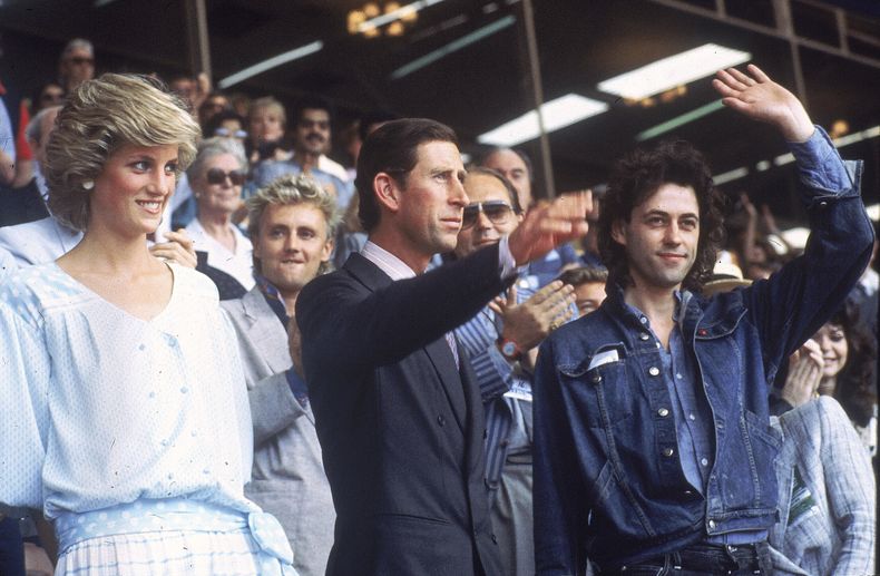 ARCHIVO - La princesa Diana, a la izquierda, y el príncipe Carlos asisten al concierto Live Aid mientras saludan a la multitud con el organizador del evento Bob Geldof, a la derecha, en el estadio de Wembley de Londres, el 13 de julio de 1985. (Foto AP/Joe Schaber, archivo)