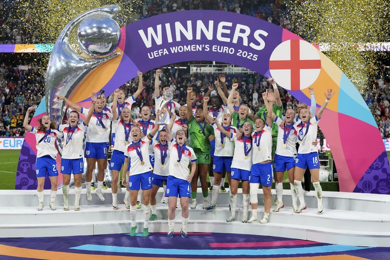 Leah Williamson, centro izquierda, y Keira Walsh de Inglaterra levantan el trofeo después de ganar el partido de fútbol de la final de la Eurocopa Femenina 2025 entre Inglaterra y España en el St. Jakob-Park en Basilea, Suiza, el domingo 27 de julio de 2025. (AP Photo/Alessandra Tarantino)