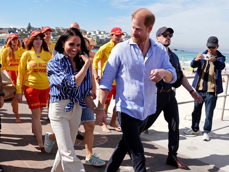 ARCHIVO - El príncipe Enrique y Meghan, los duques de Sussex, caminan por el paseo marítimo tras reunirse con socorristas voluntarios del Bondi Surf Bathers Life Saving Club, durante una visita a la playa de Bondi, en Australia, el viernes 17 de abril de 2026. (Jonathan Brady/Pool Photo via AP, archivo)