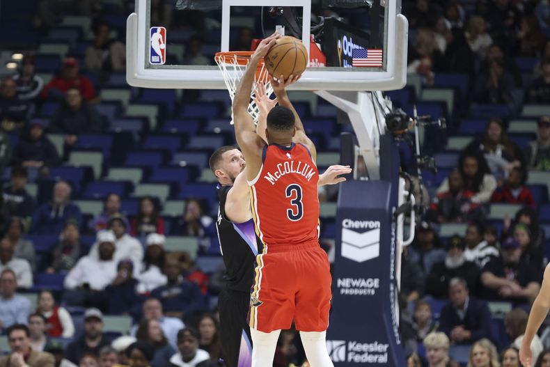 El escolta de los Pelicans de Nueva Orleans CJ McCollum (3) dispara un triple sobre el escolta del Jazz de Utah, Svi Mykhailiuk, en la primera mitad de un partido de baloncesto de la NBA en Nueva Orleans, el lunes 20 de enero de 2025. (AP Foto/Peter Forest)