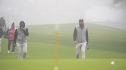 Los estadounidenses Collin Morikawa (izquierda) y Scottie Scheffler caminan en medio de la niebla hacia el primer green, el sábado 28 de septiembre de 2024, en la Copa Presidentes que se realiza en Montreal, Canadá (Christinne Muschi/The Canadian Press via AP)