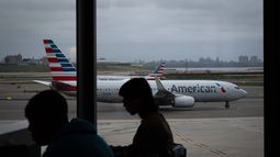 Gente esperando a vuelos mientras un avión de American Airlines circula por la pista en el aeropuerto LaGuardia (LGA) en el barrio de Queens, Nueva York, el domingo 9 de noviembre de 2025. (AP Foto/Adam Gray)