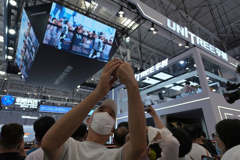 Personas se toman selfies en la Conferencia sobre Robótica en Beijing, el 20 de agosto del 2026. (AP foto/Ng Han Guan)