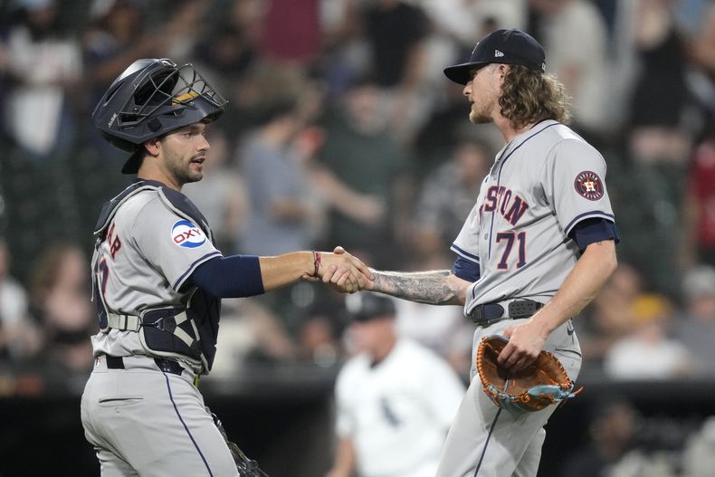 El receptor de los Astros de Houston, César Salazar, y el lanzador relevista Josh Hader celebran la victoria del equipo por 4-1 sobre los Medias Blancas de Chicago el miércoles 19 de junio de 2024, en Chicago. (AP Foto/Charles Rex Arbogast)