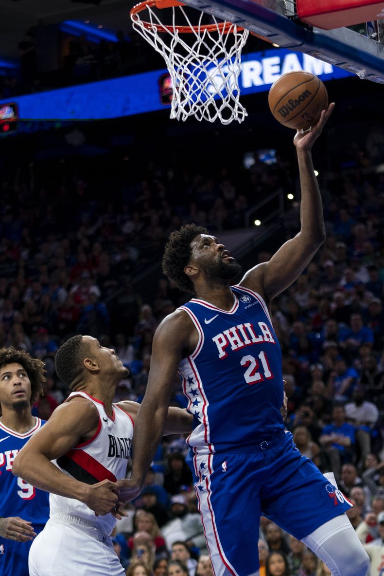 Joel Embiid de los 76ers de Filadelfia lanza el balón hacia la canasta mientras Malcolm Brodgon de los Trail Blazers de Portland le comete una falta en el encuentro del domingo 29 de octubre del 2023. (AP Foto/Chris Szagola)