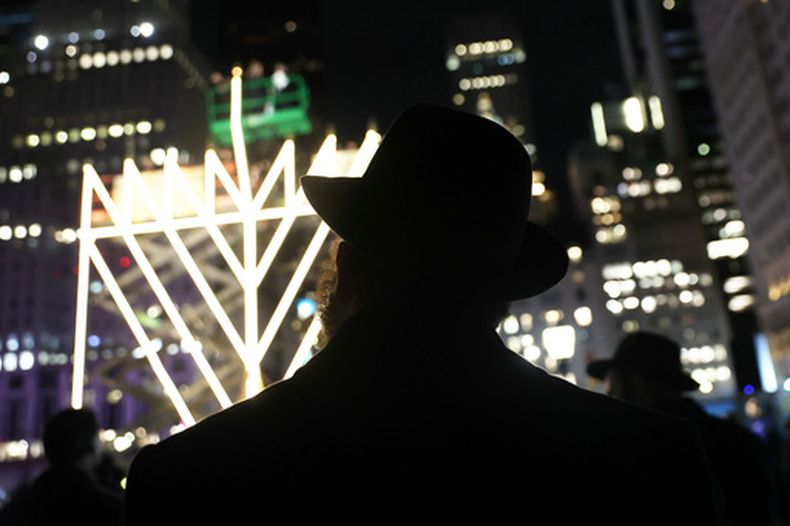 ARCHIVO - Varias personas observan el encendido de la menorá más grande del mundo en la Quinta Avenida, junto a Central Park, durante la séptima noche de Janucá, el 31 de diciembre de 2024, en Nueva York. (AP Foto/Heather Khalifa, archivo)