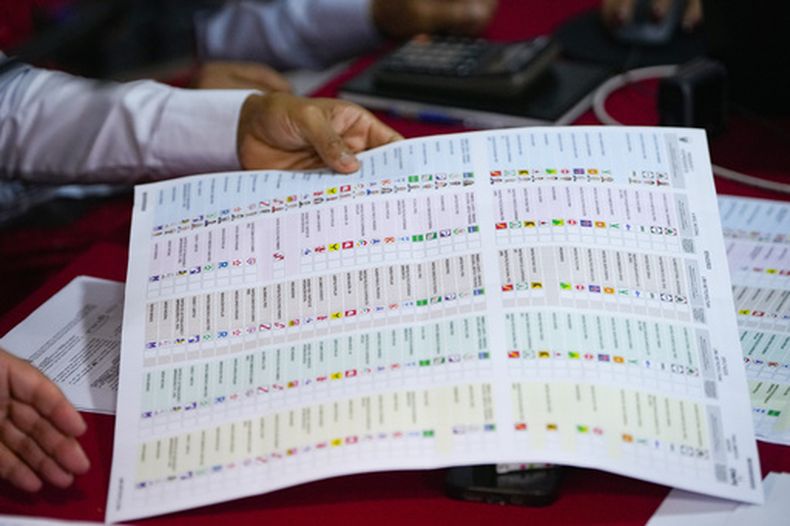 Un miembro designado por el Jurado Electoral Especial analiza una papeleta durante un recuento de votos de las elecciones generales en Lima, Perú, el miércoles 22 de abril de 2026. (AP Foto/Guadalupe Pardo)