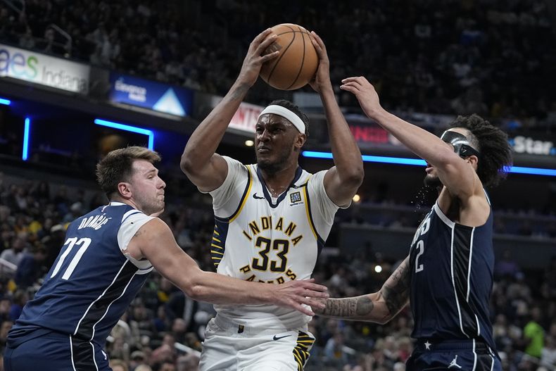 El ala-pívot de los Pacers de Indiana Myles Turner (33) se dirige al aro ante Luka Doncic (77) y Dereck Lively II de los Mavericks de Dallas, durante la segunda mitad del juego de baloncesto de la NBA, el domingo 25 de febrero de 2024, en Indianápoolis. (AP Foto/Darron Cummings)