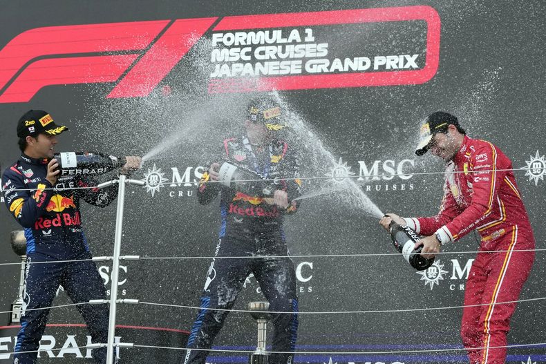 Max Verstappen de Red Bull (centro), luego de ganar el Gran Premio de Japón, recibe un baño de champaña de parte de Sergio Pérez (izquierda) de Red Bull y Carlos Sainz (Ferrari), el domingo 7 de abril de 2024. (AP Foto/Hiro Komae)