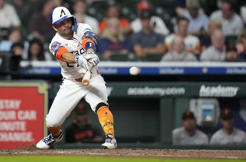 Jose Altuve, de los Astros de Houston, batea un sencillo frente a Spencer Bivens, relevista de los Gigantes de San Francisco, durante la octava entrada del juego de béisol de Grandes Ligas el lunes 31 de marzo de 2025, en Houston. (AP Foto/Karen Warren)