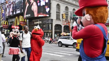 americateve | Un visitante de Times Square posa para un retrato con personas disfrazadas de personajes famosos el lunes 28 de julio de 2014 en Nueva York. El alcalde de Nueva York Mayor Bill de Blasio dijo el lunes que considera que la gente que trabaja disfrazada en T