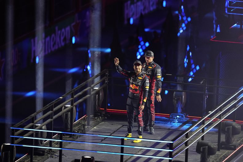 El holandés Max Verstappen y el mexicano Sergio Pérez, de la escudería Red Bull, saludan durante la ceremonia de apertura de las actividades del Gran Premio de Las Vegas, el miércoles 15 de noviembre de 2023 (AP Foto/Darron Cummings)
