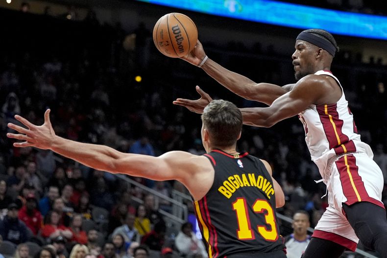 Jimmy Butler, del Heat de Miami, envía un pase frente a Bogdan Bogdanovic, de los Hawks de Atlanta, en el encuentro del martes 9 de abril de 2024 (AP Foto/Mike Stewart)