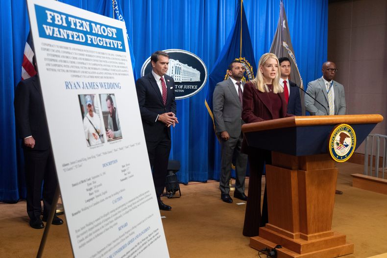 La secretaria de Justicia Pam Bondi junto a un cartel con la información del prófugo canadiense Ryan James Wedding durante una conferencia de prensa en el Departamento de Justicia, el miércoles 19 de noviembre de 2025, en Washington. (AP Foto/Mark Schiefelbein)
