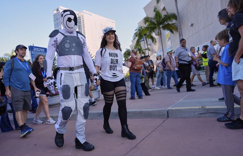 Chris Lane, a la izquierda, y su esposa Shannon, con disfraces inspirados en la serie Murderbot de Apple TV+, caminan entre en la noche de vista previa internacional de la Comic-Con 2025 el miércoles 23 de julio de 2025 en San Diego. (Foto AP/Chris Pizzello)