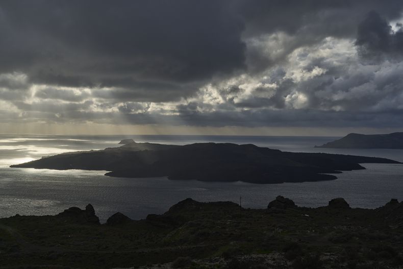 Los rayos del sol iluminan el islote volcánico de Nea Kameni, parte de la isla de Santorini afectada por el terremoto, Grecia, martes 4 de febrero de 2025. (AP foto/Petros Giannakouris)