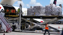 Personas cargan pales con alimentos y kits de higiene en un avión con destino a Cuba organizado por el gobierno de Estados Unidos. (AP Foto/Lynne Sladky)