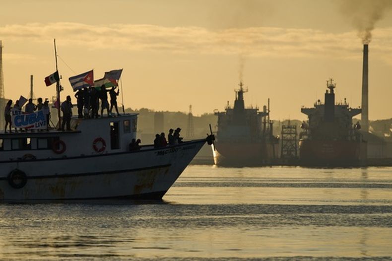 Activistas ondean banderas cubanas y palestinas desde el buque Maguro, que llega procedente de México con ayuda humanitaria como parte del convoy Nuestra América, en la bahía de La Habana, Cuba, el martes 24 de marzo de 2026. (AP Foto/Ramón Espinosa)
