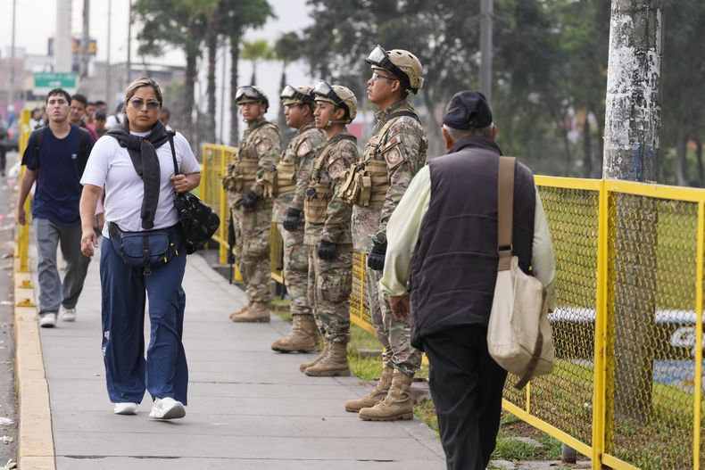 Peatones pasan junto a soldados que custodiaban un puente en Lima, Perú, el martes 18 de marzo de 2025, después de que la presidenta Dina Boluarte declarara el estado de emergencia tras el asesinato de un popular cantante en medio de un repunte de la violencia en la capital. (Foto AP/Martín Mejía)